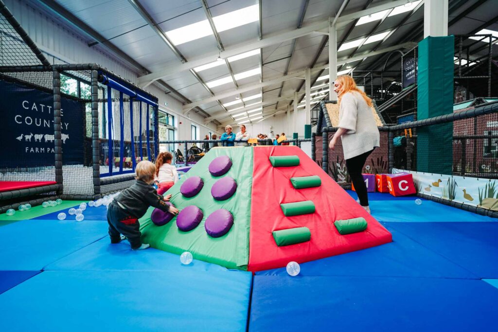 CHILDREN PLAYING IN A FARM THEMED INDOOR PLAY AREA